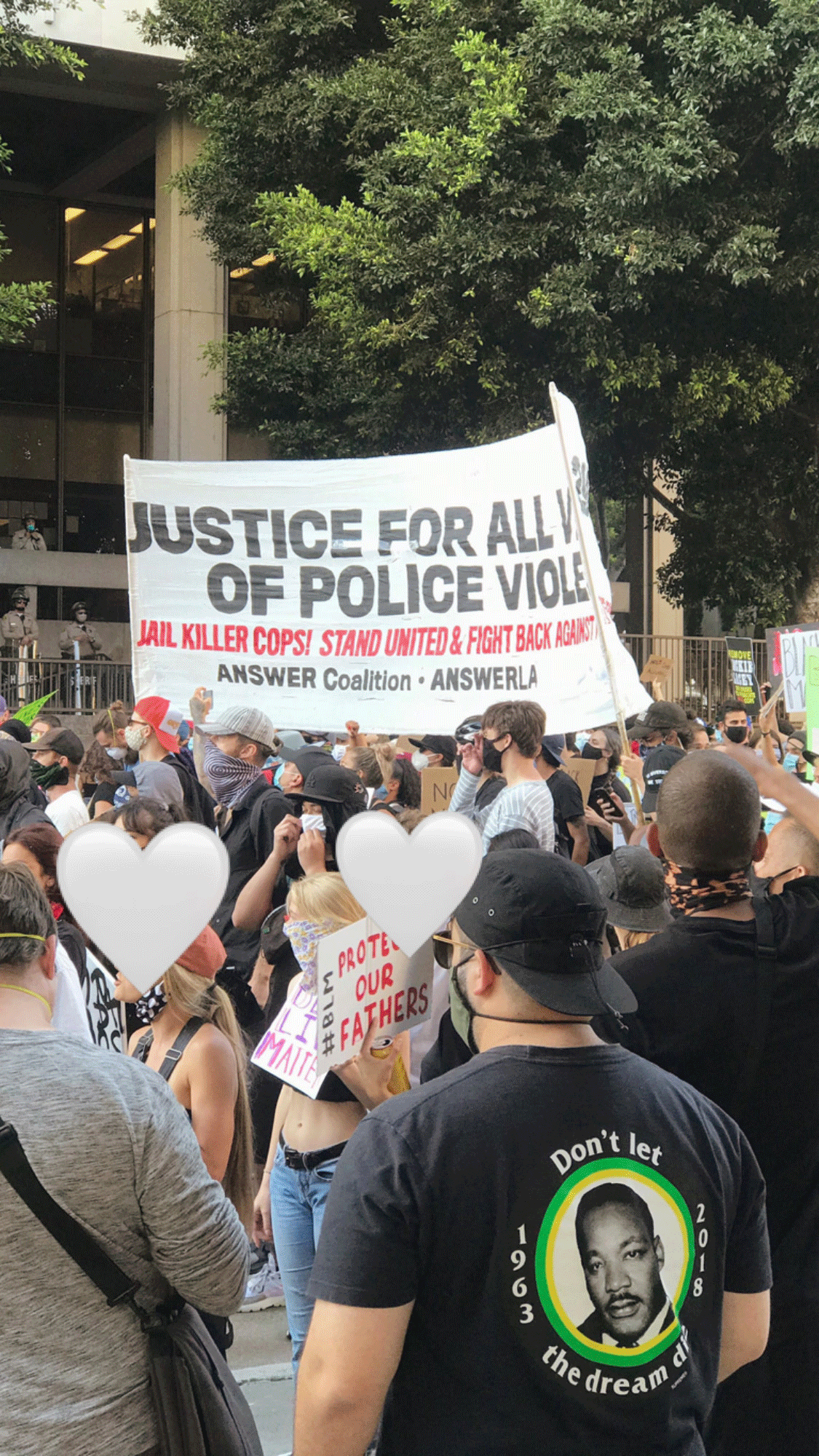 Masked protesters holding a large banner reading “JUSTICE FOR ALL” in front of a city building during a Black Lives Matter demonstration