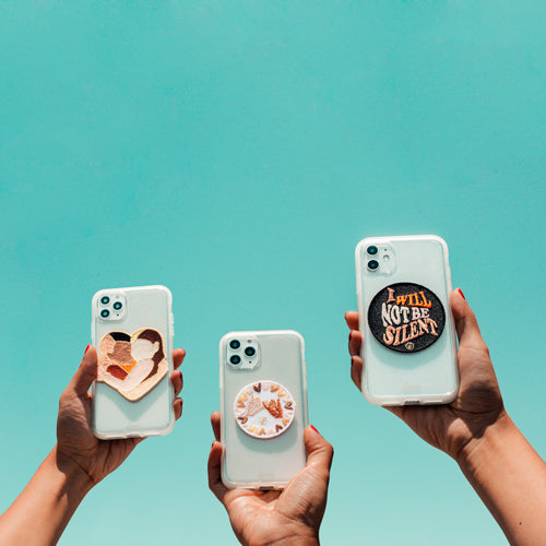 Front view of three clear iPhone cases showing Sonix Unity 3-piece patch set with a heart patch, a floral round patch, and an ‘I WILL NOT BE SILENT’ patch against a teal sky
