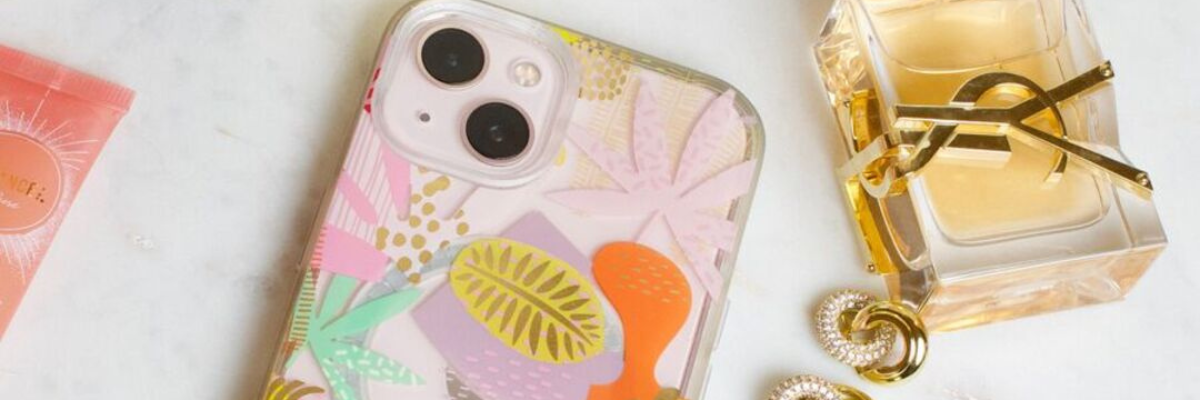 Angled top-down view of an iPhone in pastel floral case beside perfume and jewelry on marble