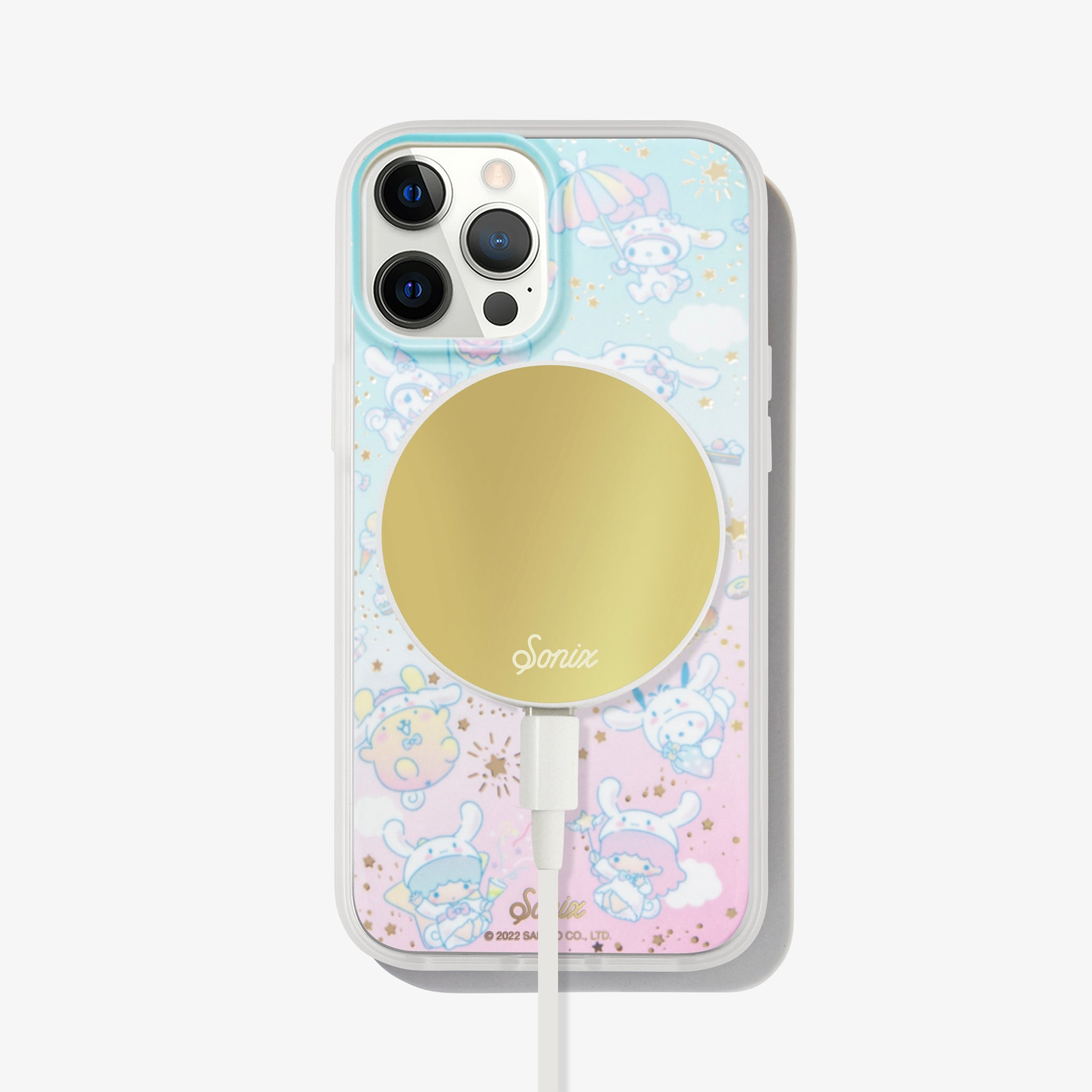 Pink and blue iphone case with gold stars, clouds, and hello kitty character cinnamoroll on an iphone 12 pro with gold magsafe charger on the back 