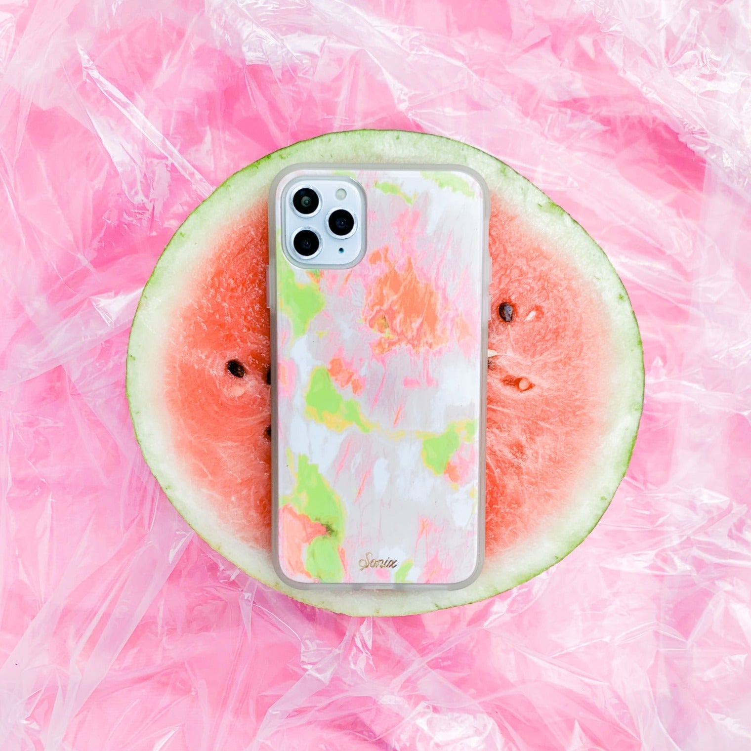 Watermelon Glow iPhone Case - Glow in the dark bumper with pink and green paint splots across the case - on a watermelon and pink background
