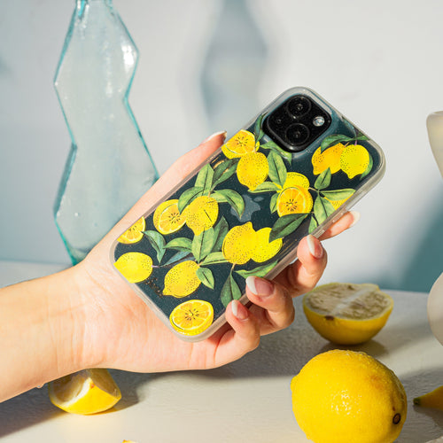 Lemons with green foliage and gold foiling shown on a black iphone 13 with a hand holding the phone