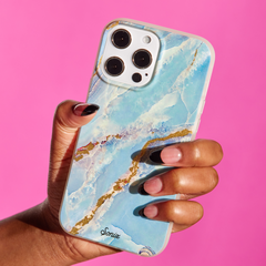 blue marble with gold glitter metallic veins being held by a hand with a pink background