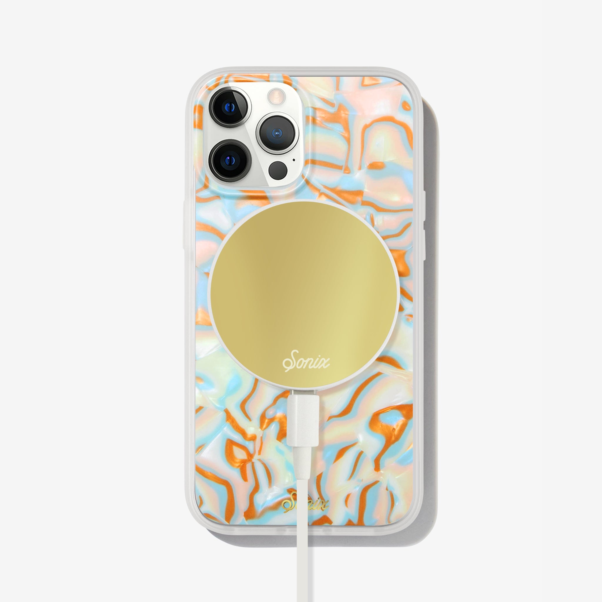 metallic oranges, blues, and cream colors in a wavy 70's pattern shown on an iphone 13 with a gold maglink charger on the back