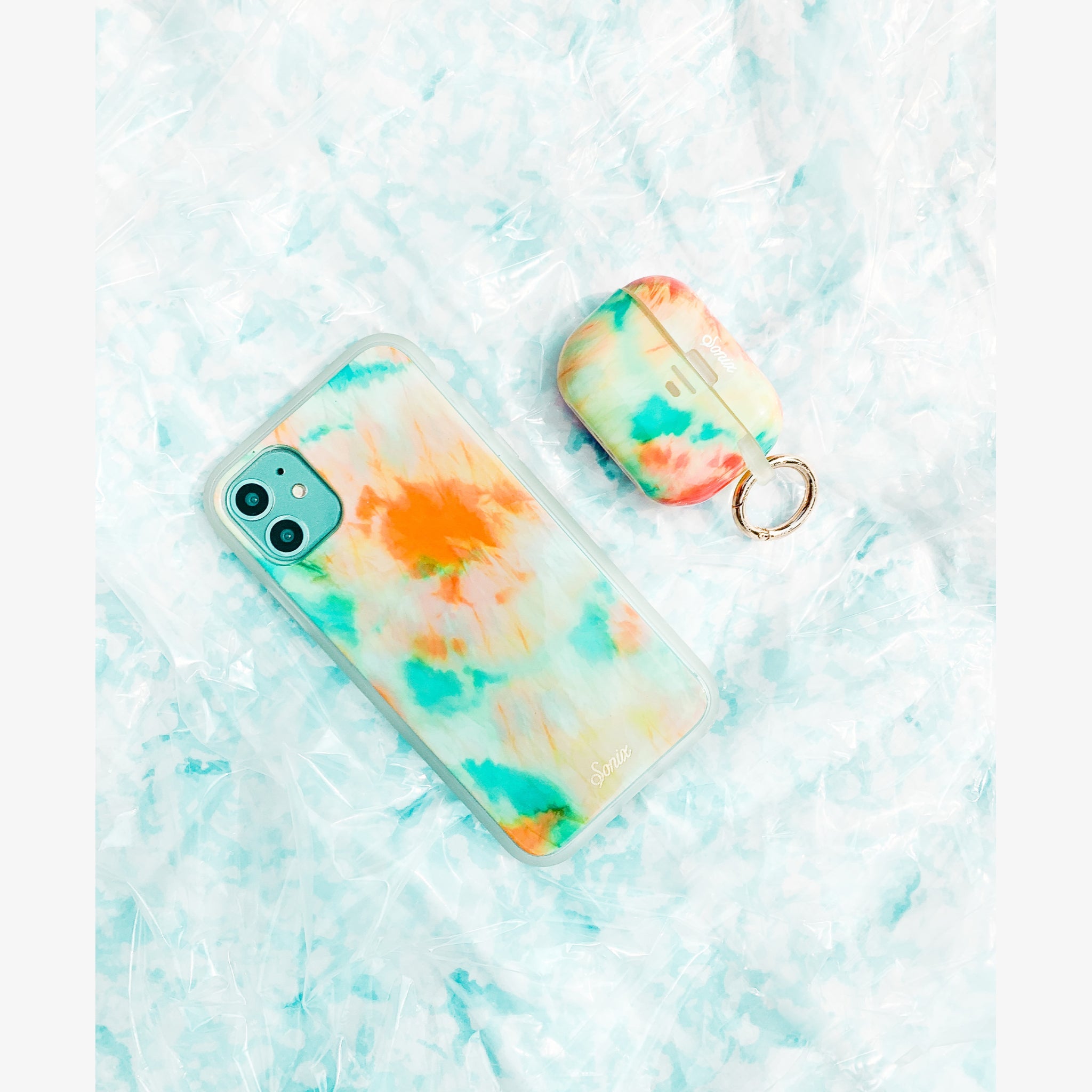 orange and blue tie-dye design that glows in the dark shown on an iphone and airpods